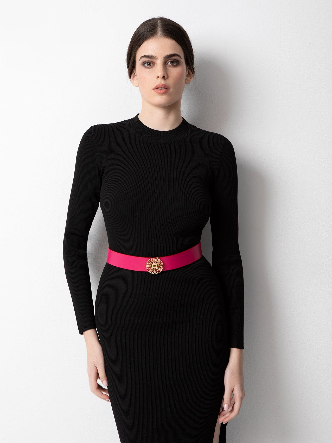 Young slim woman with black hair in a black long sleeve dress with pink belt