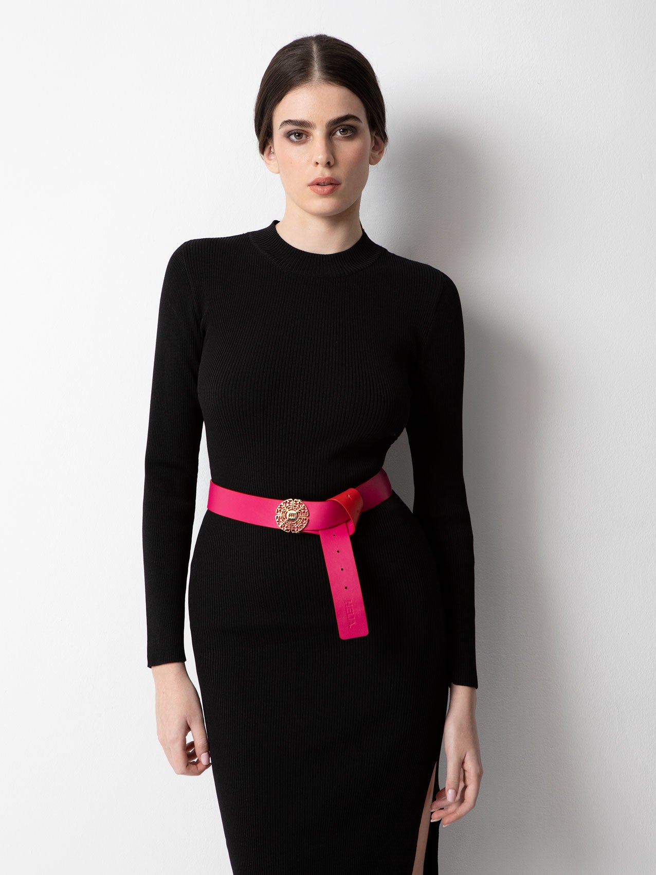 Young slim woman with black hair in a black long sleeve dress with pink belt