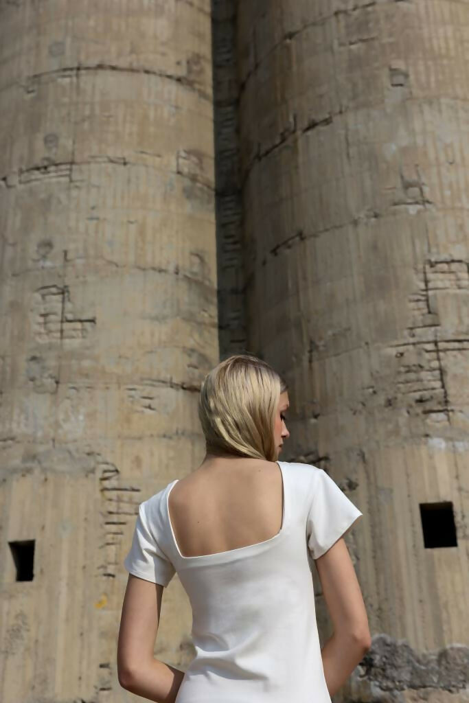 A young blonde woman in White Midi Dress standing with her back 